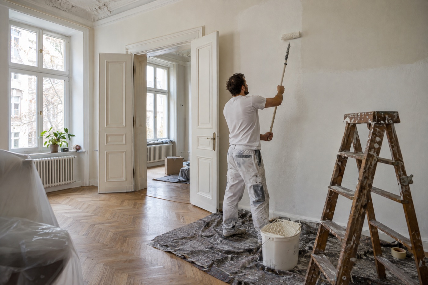 Maler rollt frische Farbe auf eine Altbauwand
